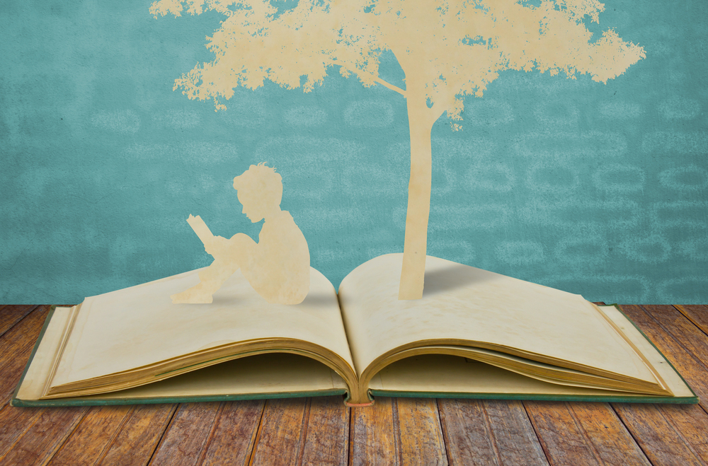Silhouettes of a tree and a man on a book